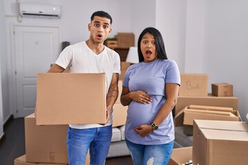 Fototapeta na wymiar Young hispanic couple expecting a baby moving to a new home in shock face, looking skeptical and sarcastic, surprised with open mouth