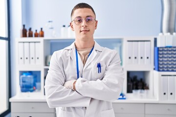 Fototapeta premium Young hispanic man scientist smiling confident standing with arms crossed gesture at laboratory