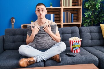 Young man eating popcorn puffing cheeks with funny face. mouth inflated with air, catching air.