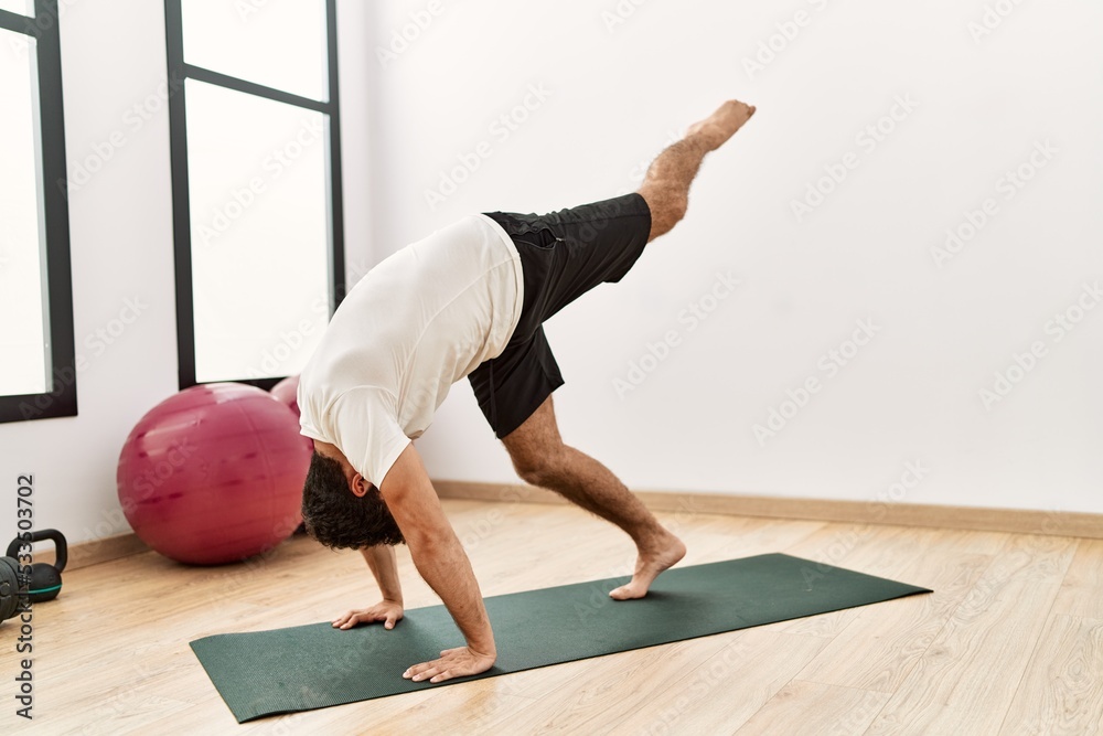 Wall mural young hispanic man stretching at sport center