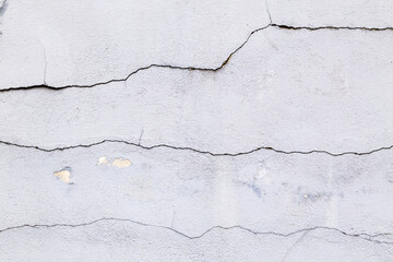 Obraz premium Textured grey white, concrete wall with three horizontal cracks and grungy, rough painted, detail. Design element abstract background with holes, scratches and weathering.