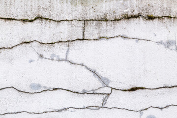Textured grey white, concrete wall with heavy black cracks and grungy, rough painted, detail. Design element abstract background with holes, paint patches, scratches and weathering.