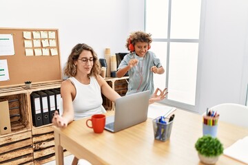 Mother and son doing yoga exercise while child listen music at office