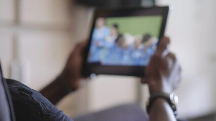 Young black man watching a soccer match tablet computer - Powered by Adobe
