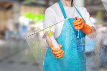 Cleaner wipes the glass with a tool on a blurred background.