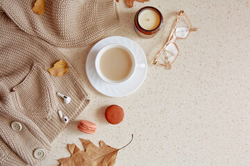 Obraz na płótnie Canvas Woman autumn outfit - casual sweater and glasess with headphones. Aesthetic coffee time among candle, fall leaves, macaroons. Copy space