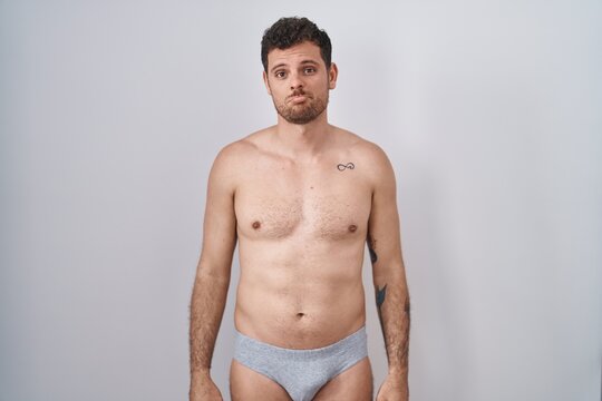 Young hispanic man standing shirtless wearing underware depressed and worry for distress, crying angry and afraid. sad expression.