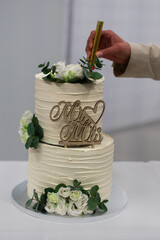 Jemand dekoriert eine mehrstöckige Hochzeitstorte mit echten Rosen in einer Bäckerei