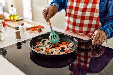Senior man cooking at kitchen