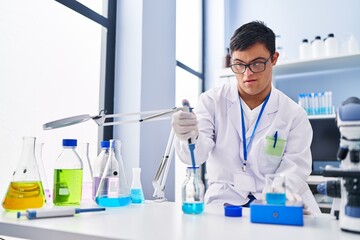 Down syndrome man wearing scientist uniform measuring liquid at laboratory