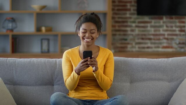 Funny internet content. Happy african american woman reading news online on smartphone and laughing, free space