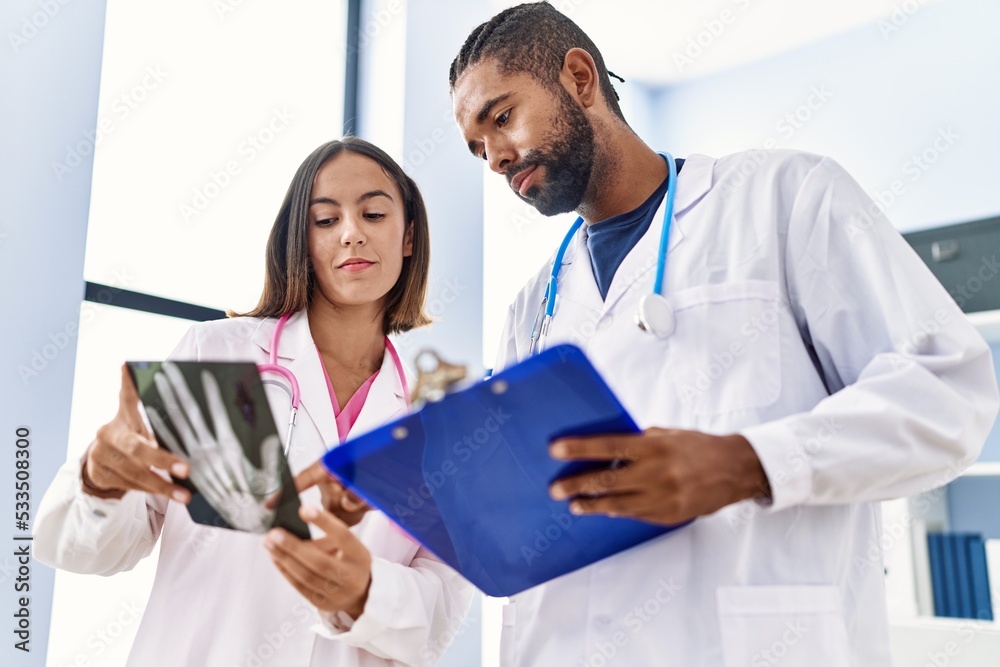 Wall mural Man and woman wearing doctor uniform looking xray working at clinic