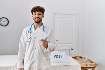 Young arab man wearing doctor uniform holding vote at electoral college