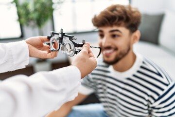 Young arab man smiling confident reciving optometrist glasses at home