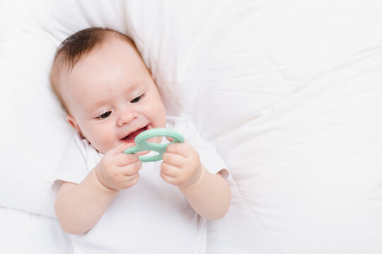 A baby with a teether on a white background . Teething. Children's article.