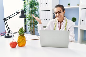 Young hispanic woman working at dietitian clinic celebrating achievement with happy smile and...