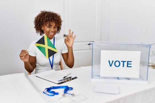 Young african american woman at political campaign election holding jamaica flag doing ok sign with fingers, smiling friendly gesturing excellent symbol