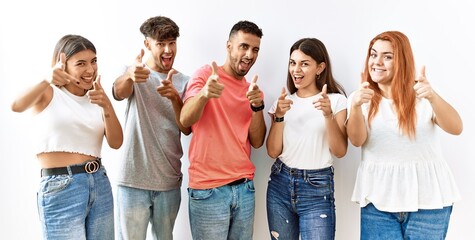 Group of young friends standing together over isolated background pointing fingers to camera with happy and funny face. good energy and vibes.