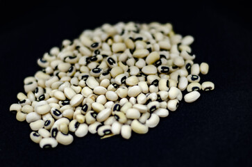 Dried cowpea grains standing on black background, isolated