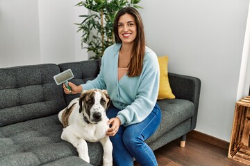Young woman smiling confident using pet hair remover brush at home