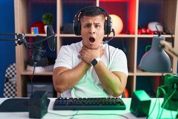Young hispanic man playing video games shouting suffocate because painful strangle. health problem. asphyxiate and suicide concept.