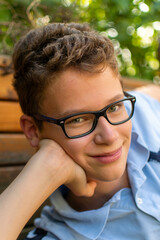 European boy with glasses and curls beams at the camera