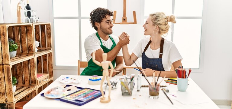 Young artist couple smiling happy shaking hands at art studio.
