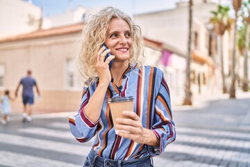 Middle age blonde woman talking on the smartphone drinking coffee at street