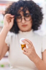 Young middle eastern woman customer reading pills label at pharmacy