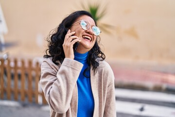 Young chinese woman smiling confident talking on the smartphone at street