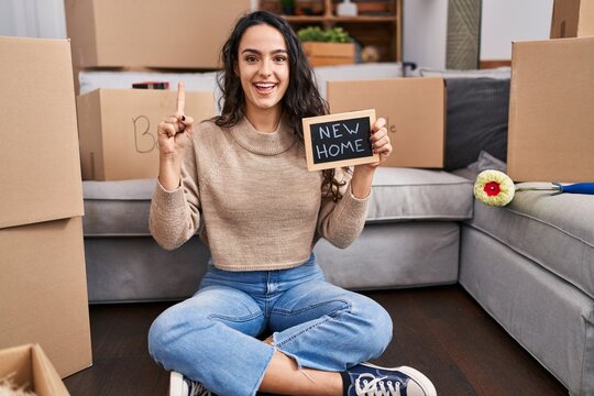 Young brunette woman moving to a new home smiling with an idea or question pointing finger with happy face, number one