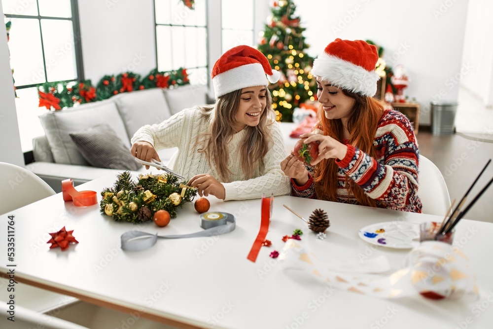 Poster Woman couple making handmade christmas decoration sitting on the table at home