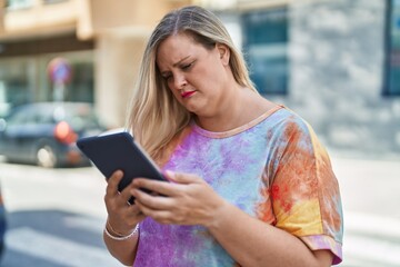 Young woman using touchpad with serious expression at street