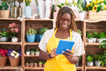 African american woman florist smiling confident using touchpad at florist
