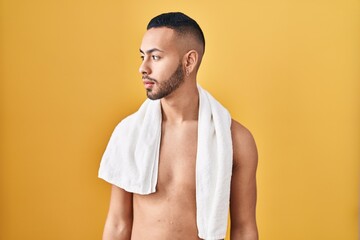 Young hispanic man standing shirtless with towel looking to side, relax profile pose with natural...