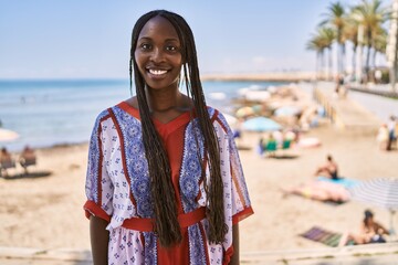 Young african american woman smiling happy standing at the beach.