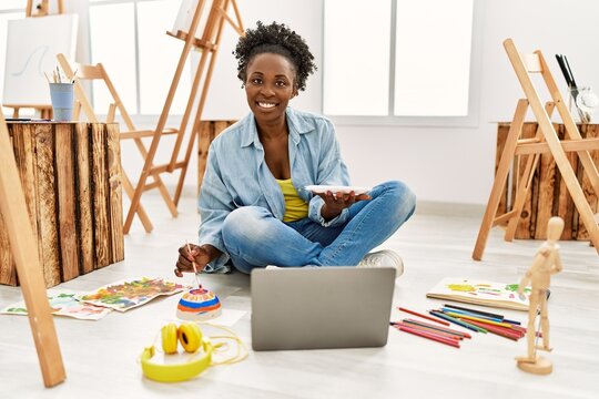 Young african american artist woman using laptop drawing at art studio.
