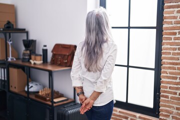 Middle age grey-haired woman business worker looking throw the window at office