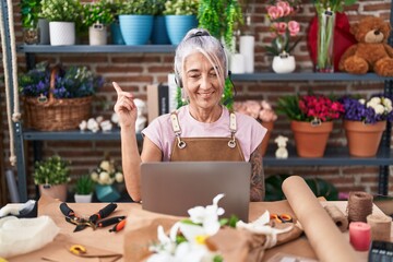 Middle age woman with tattoos working at florist shop doing video call smiling happy pointing with hand and finger to the side