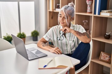 Middle age grey-haired woman smiling confident using laptop at home