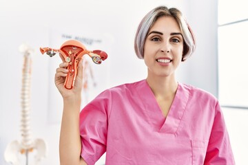 Young caucasian gynecologist woman holding fallopian tube anatomical model standing at the clinic.