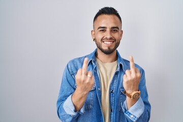 Young hispanic man standing over isolated background showing middle finger doing fuck you bad...