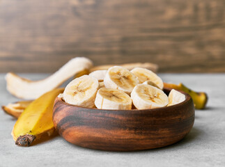 Photo of banana slices in a bowl on a concrete surface