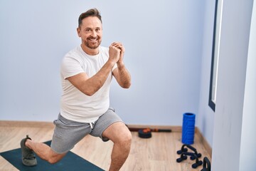 Fototapeta na wymiar Young caucasian man smiling confident training leg exercise at sport center