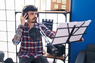 Young hispanic man artist singing song at music studio