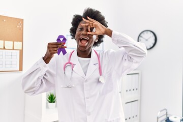 African doctor woman holding purple ribbon awareness at medical clinic smiling happy doing ok sign...