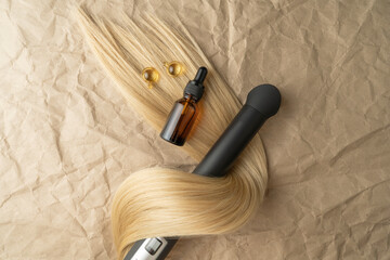 A hair treatment essential oil for smoothing hair lying on a strand of blond hair