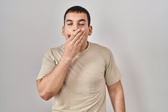 Young arab man wearing casual t shirt bored yawning tired covering mouth with hand. restless and sleepiness.