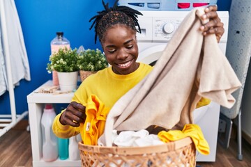 African american woman holding basket with clothes at laundry room