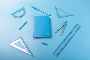 Blue chancery blue background. Monotonous blue background. Blue notepad and school items. Top view at an angle.
